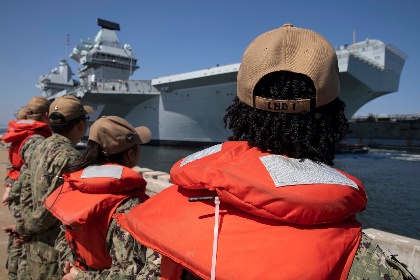 Sailors stand at parade rest on Pier 12 as HMS Queen Elizabeth (RO8) pulls into port.