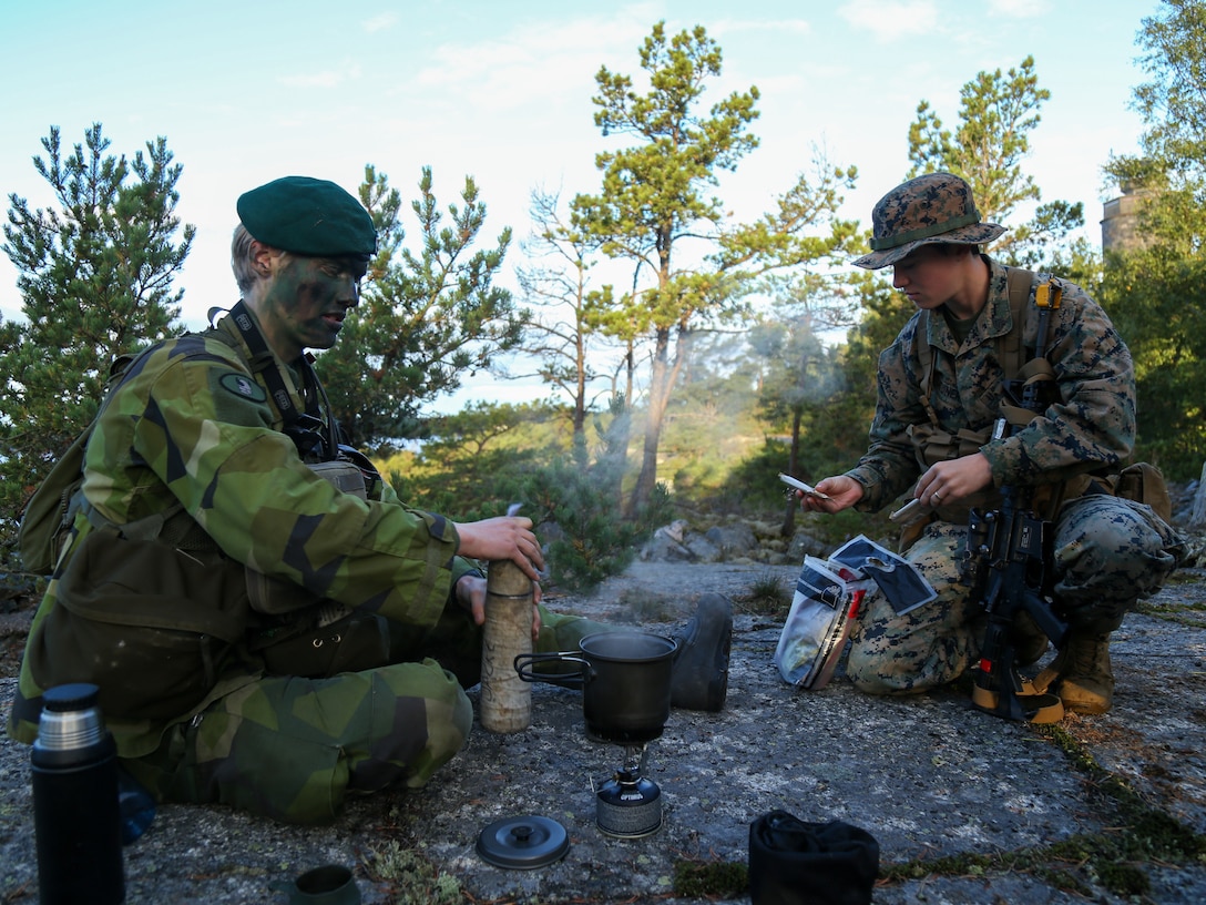 Swedish Marine Pvt. David Segelman, forward observer, with Hellfire missile platoon, 2nd Swedish Marine Battalion, and Sgt. Christine Latuner, combat engineer and Littoral Engineer Reconnaissance Team leader, 2nd Marine Logistics Battalion, share field rations and coffee, during exercise Archipelago Endeavor 22 on Berga Naval Base, Sweden, Sept. 21, 2022. AE22 is an integrated field training exercise that increases operational capability and enhances strategic cooperation between the U.S. Marines and Swedish forces.