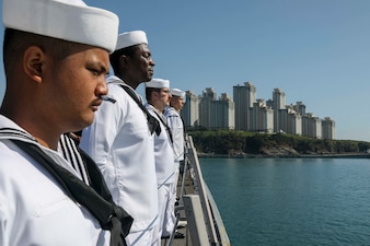 Sailors man the rails aboard USS Barry (DDG 52) as the ship arrives in Busan.