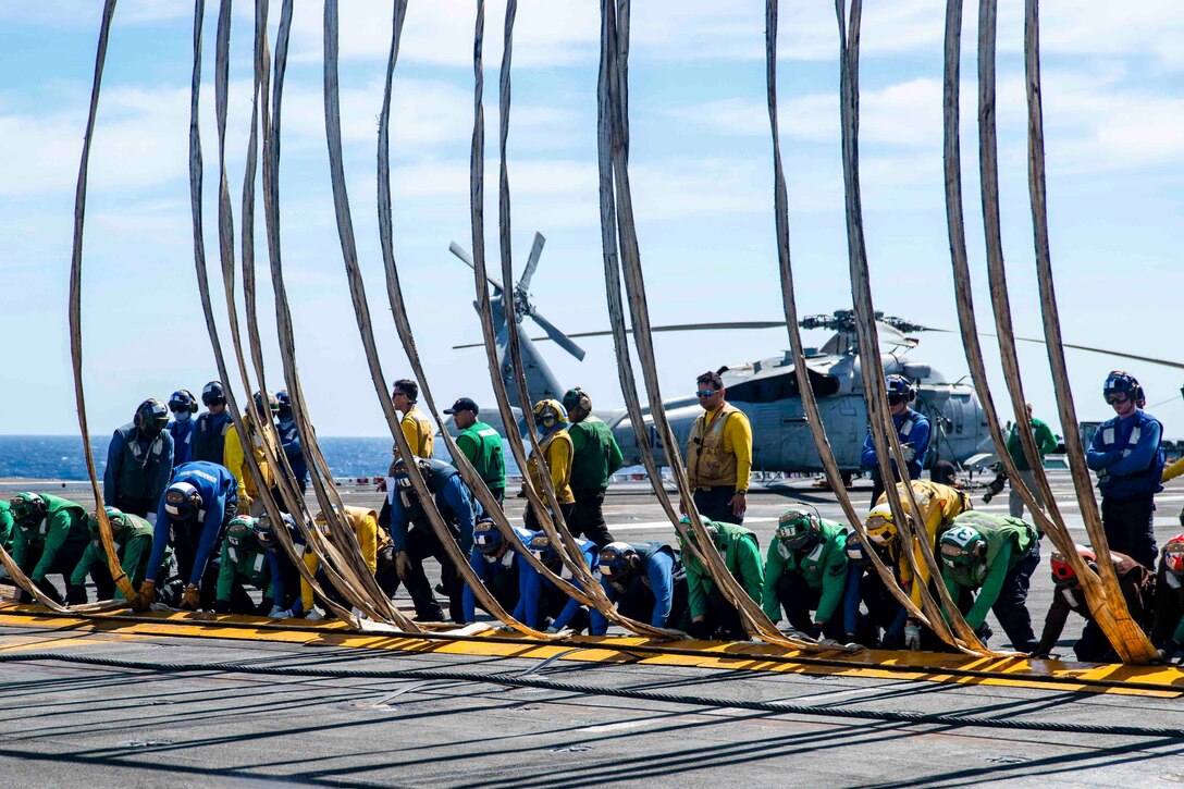 A group sailors set up a barricade on the deck of a ship.