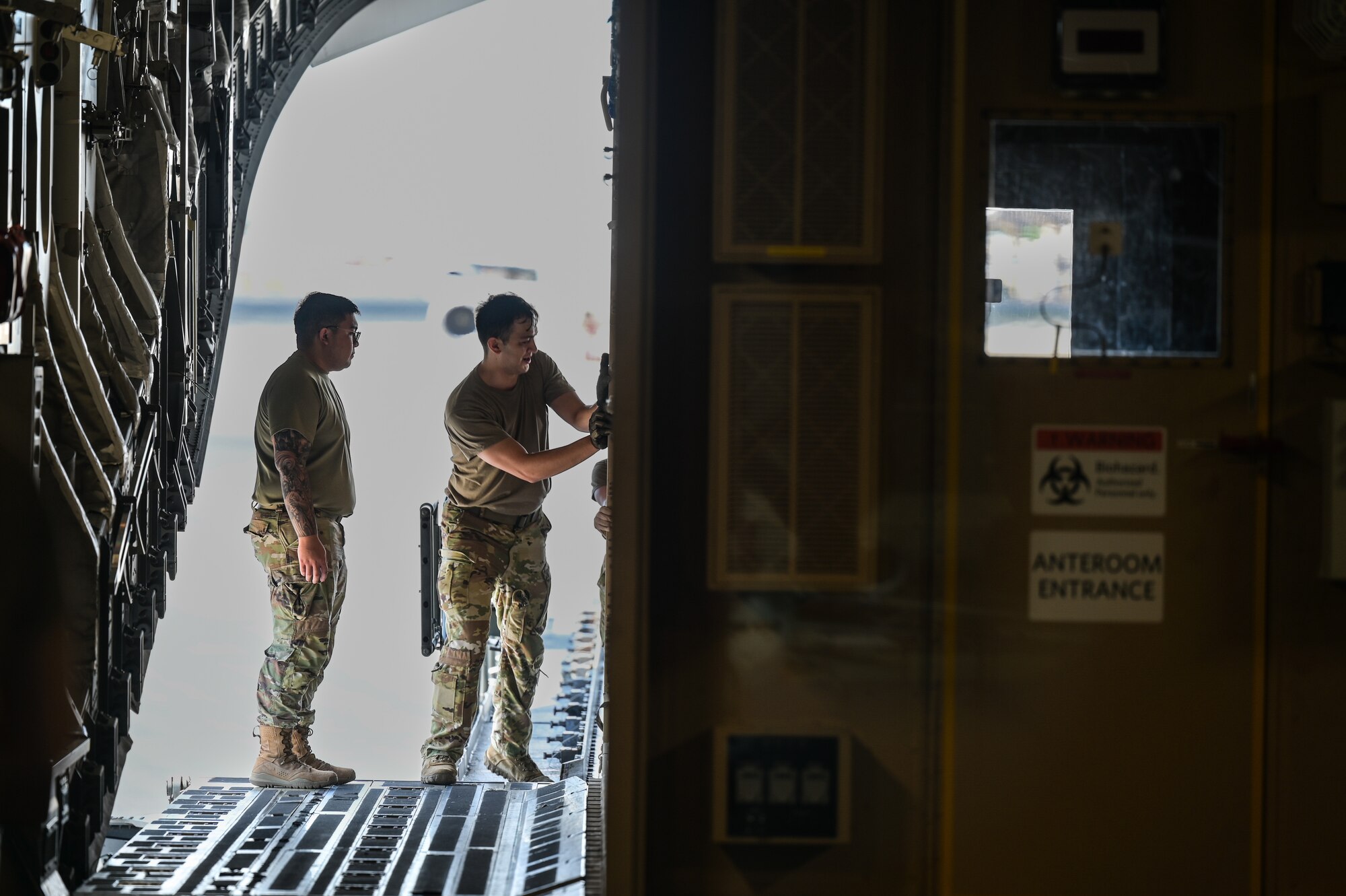 Senior Airman Damian Cavazos, 535th Airlift Squadron loadmaster, and Senior Airman Adrian Jarin, 18th Medical Group public health journeyman, guide a Negative Pressure Conex-Lite onto a C-17 Globemaster III at Joint Base Pearl Harbor-Hickam, Hawaii, Sept. 21, 2022. This was the first time that the NPCL carrying a patient was transferred between aircraft within the U.S. Pacific Air Forces area of responsibility. (U.S. Air Force photo by Staff Sgt. Alan Ricker)