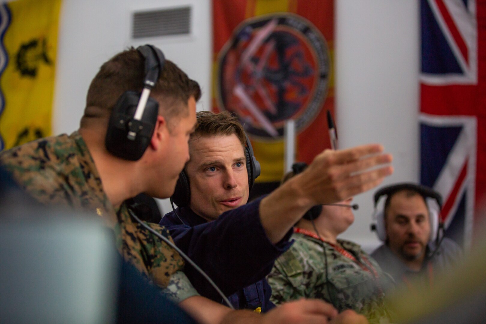 U.S. Marine Corps Maj. Elliot Eggert, left, assistant fires and effects coordinator for Task Force 61/2, and U.K. Royal Navy Lt. Cdr. Steve Lovatt communicate within the the QinetiQ range control facility, Sept. 7, 2022, prior to a demonstration during Exercise Atlantic Thunder 2022 in the Hebrides Islands, Scotland.
