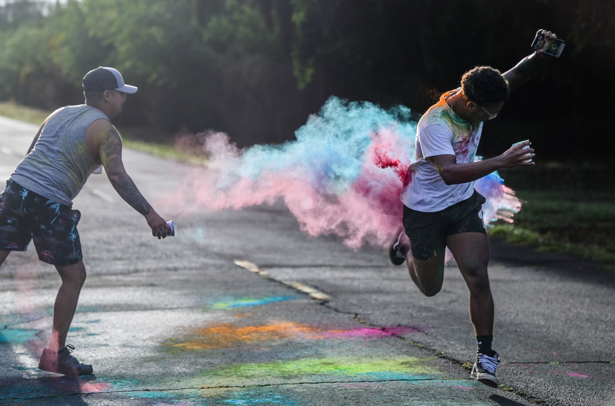 Airman 1st Class Juan Garcia, 647th Security Forces Squadron patrolman, tosses colored chalk at Airman Shawn Patton, 647th SFS installation entry controller, during a 5K Fun Run at Joint Base Pearl Harbor-Hickam, Hawaii, Sept. 23, 2022. The 15th Wing Violence Prevention Office worked with the 647th Security Forces Squadron to invite Hickam Airmen to run in support of Suicide Prevention Month. (U.S. Air Force photo by Staff Sgt. Alan Ricker)