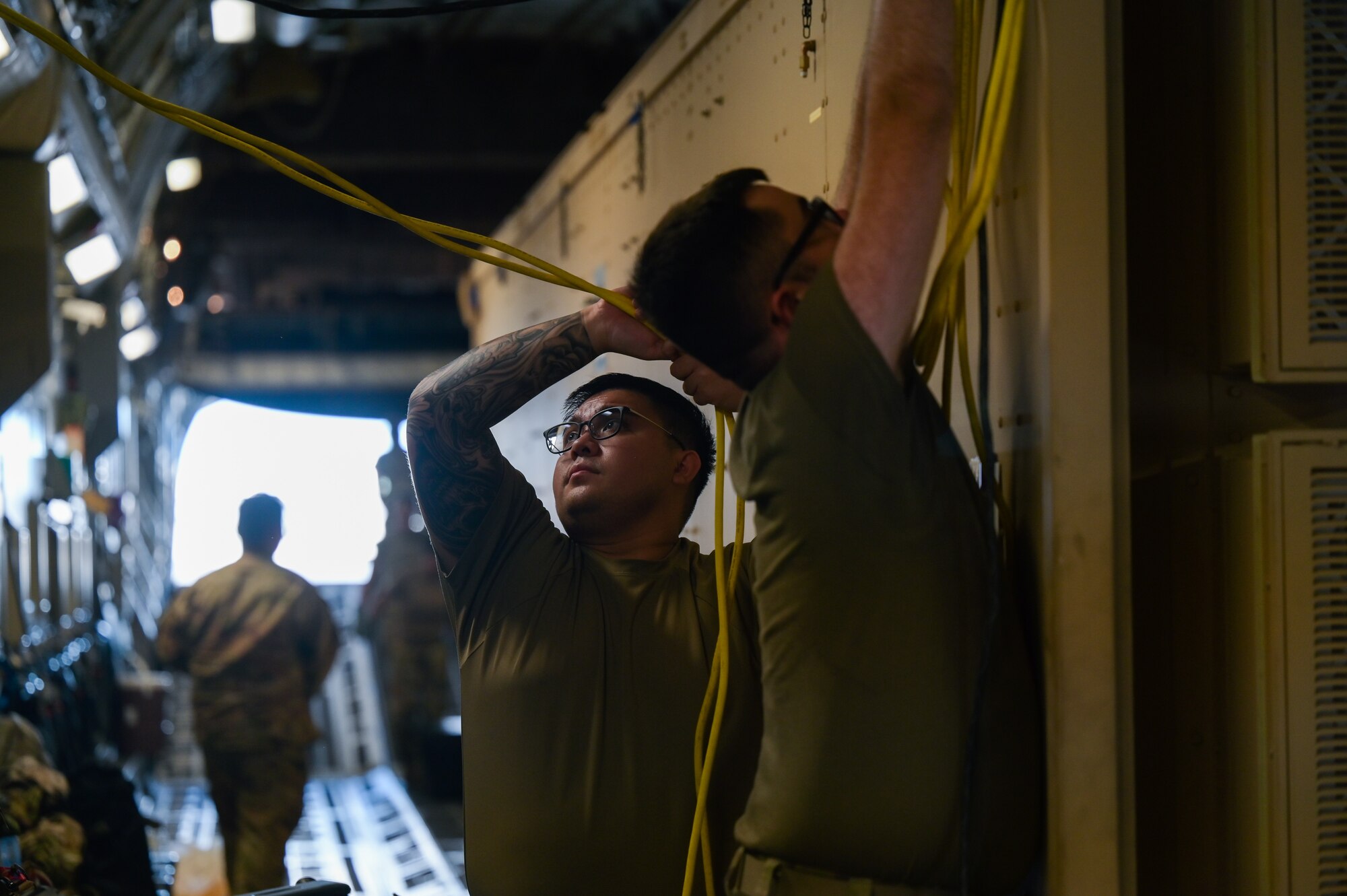 Senior Airman Adrian Jarin, 18th Medical Group public health journeyman, assists Staff Sgt. Cameron Schmidt, 18th Medical Support Squadron biomedical equipment technician, with connecting power from the C-17 Globemaster III to a Negative Pressure Conex-Lite at Joint Base Pearl Harbor-Hickam, Hawaii, Sept. 21, 2022. Jarin ensured contamination protocol was followed to minimize any or all infection while Schmidt ensured the NPCL was operational. (U.S. Air Force photo by Staff Sgt. Alan Ricker)