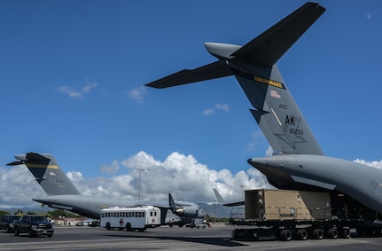 Personnel assigned to the 735th Air Mobility Squadron transport a Negative Pressure Conex-Lite from an Alaska Air National Guard 144th Airlift Squadron C-17 Globemaster III with a Tunner 60K loader at Joint Base Pearl Harbor-Hickam, Hawaii, Sept. 21, 2022. The AK ANG transported a patient from Kadena Air Base, Okinawa, Japan, to Hickam, where the 535th Airlift Squadron aircrew continued the transport to California. Airmen from the 18th Aeromedical Evacuation Squadron and 18th Medical Group provided patient care on the aircraft, while the 15th Medical Group provided an En Route Patient Staging System during the aircraft swap. (U.S. Air Force photo by Staff Sgt. Alan Ricker)