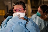 Maj. Emmy Greenhill, 18th Aeromedical Evacuation Squadron critical air transport team member, dons personal protective equipment before attending to a patient within a Negative Pressure Conex-Lite at Joint Base Pearl Harbor-Hickam, Hawaii, Sept. 21, 2022. Members assigned to the 18th AES and 18th Medical Group accompanied the patient from Kadena Air Base, Okinawa, Japan, to San Diego, California. (U.S. Air Force photo by Staff Sgt. Alan Ricker)