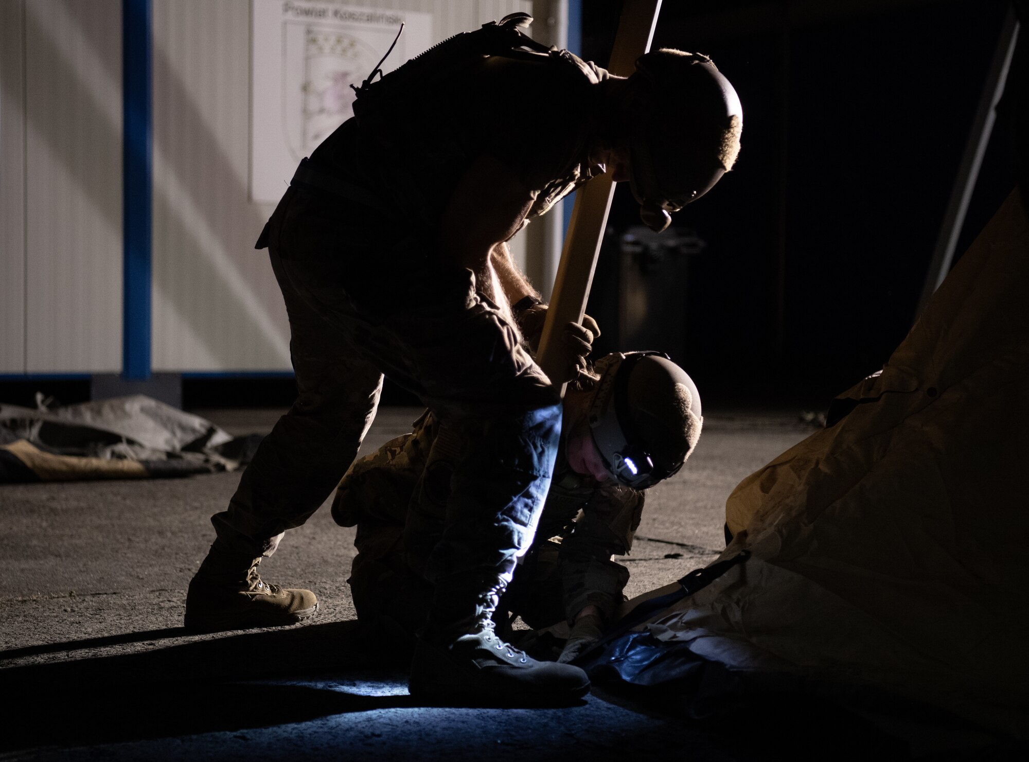 U.S. Air Force Staff Sgt. Louis Lotfy, standing, 435th Contingency Response Squadron aerial port operations noncommissioned officer in charge, and Airman Olivia Wacaser, 435th CRS mobile aerial port journeyman, connect the leg of a tent to a frame during exercise Agile Wolf 22 at Koszalin, Poland, Sept. 12, 2022. Exercise Agile Wolf is a scalable airfield opening exercise that provides a variety of training opportunities, promotes innovation, and strengthens partnerships within the 435th Air Ground Operations Wing and around Ramstein Air Base, Germany.  (U.S. Air Force photo by Airman 1st Class Jared Lovett)