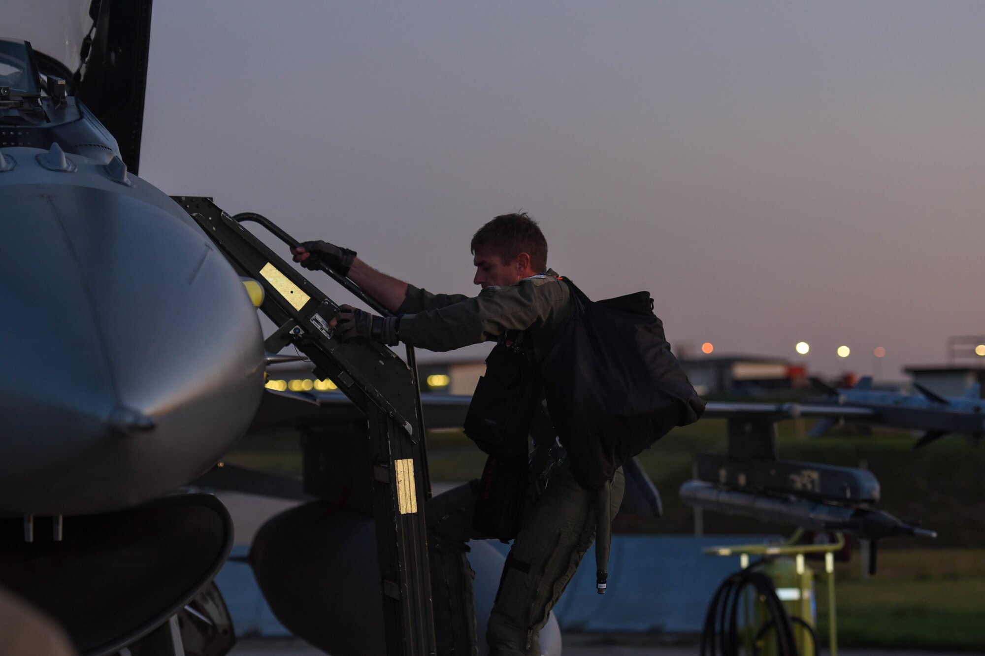 A pilot enters the cockpit of an aircraft.