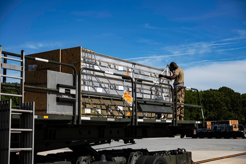A uniformed service member straps supplies on a truck.