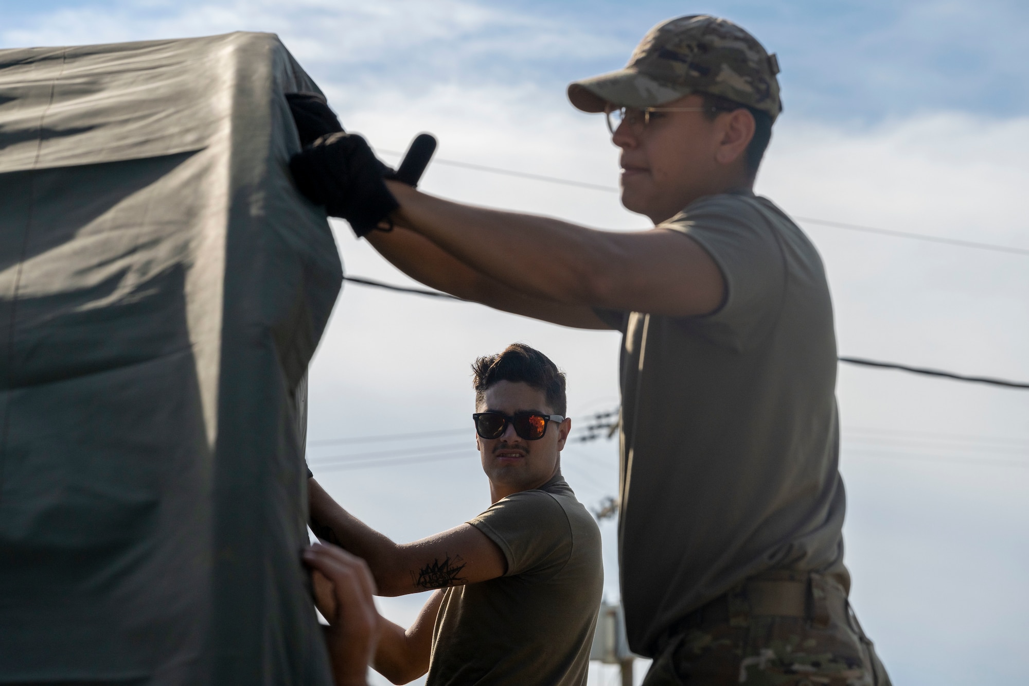 Airman 1st Class Cason Sawyer, 4th Equipment Maintenance Squadron aerospace ground equipment specialist, and Senior Airman Alejandro Soto, 336th Fighter Generation Squadron weapons load crew member, secure a tent cover during a Multi-Capable Airman exercise at Seymour Johnson Air Force Base, North Carolina, Sept. 14, 2022. Airmen participating in the exercise learned how to construct a tent intended for a command center and medical facility. (U.S. Air Force photo by Senior Airman Kevin Holloway)