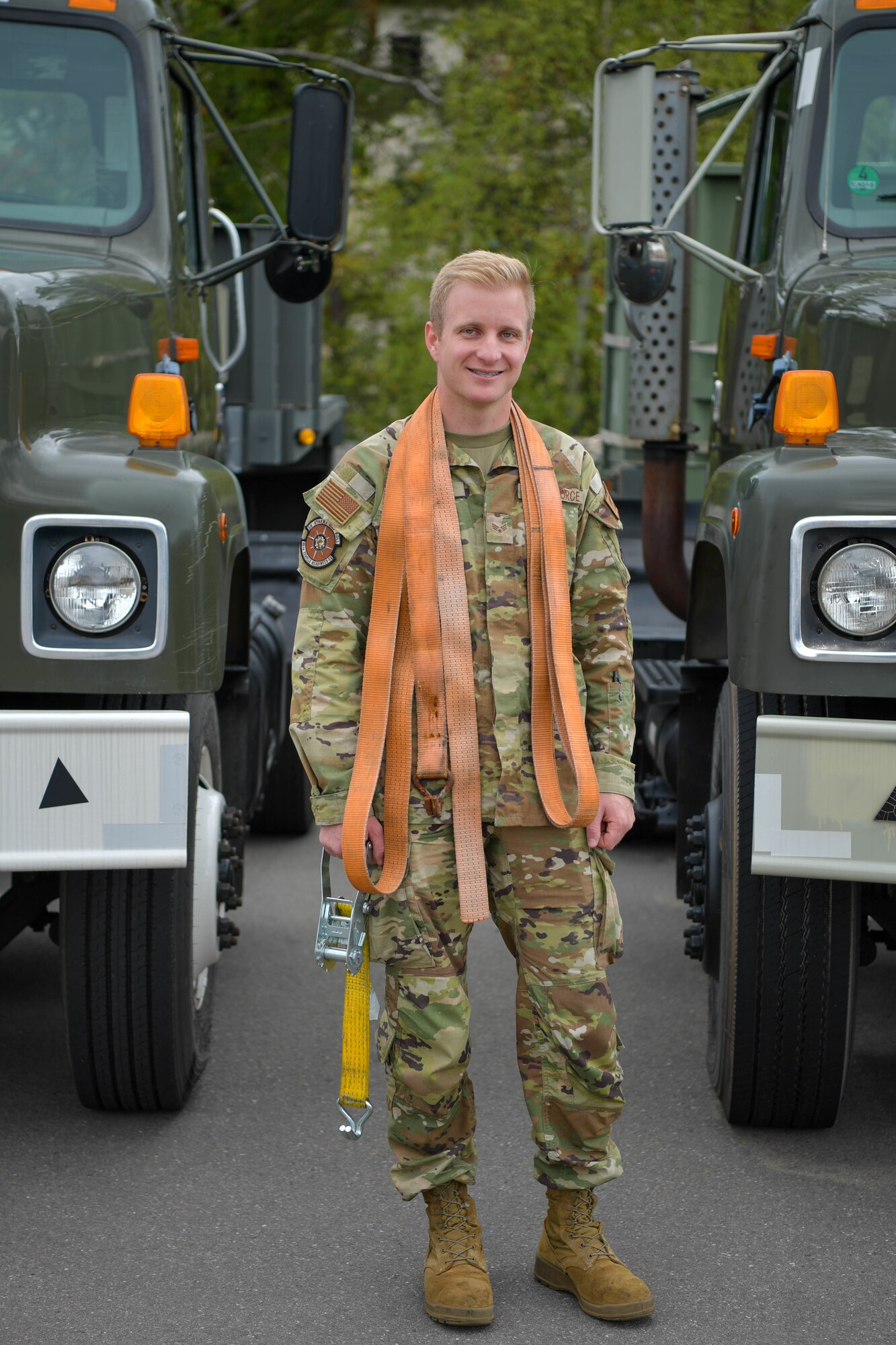 Airman stands between two industrial vehicles