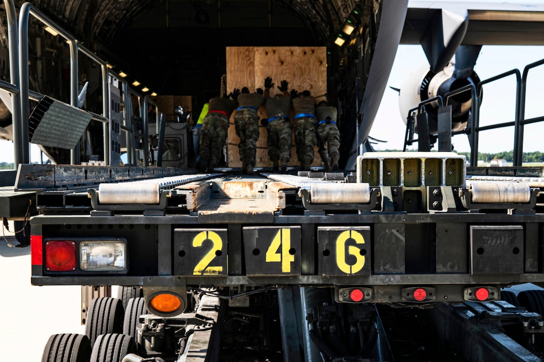 Uniformed service members load a pallet onto a plane.