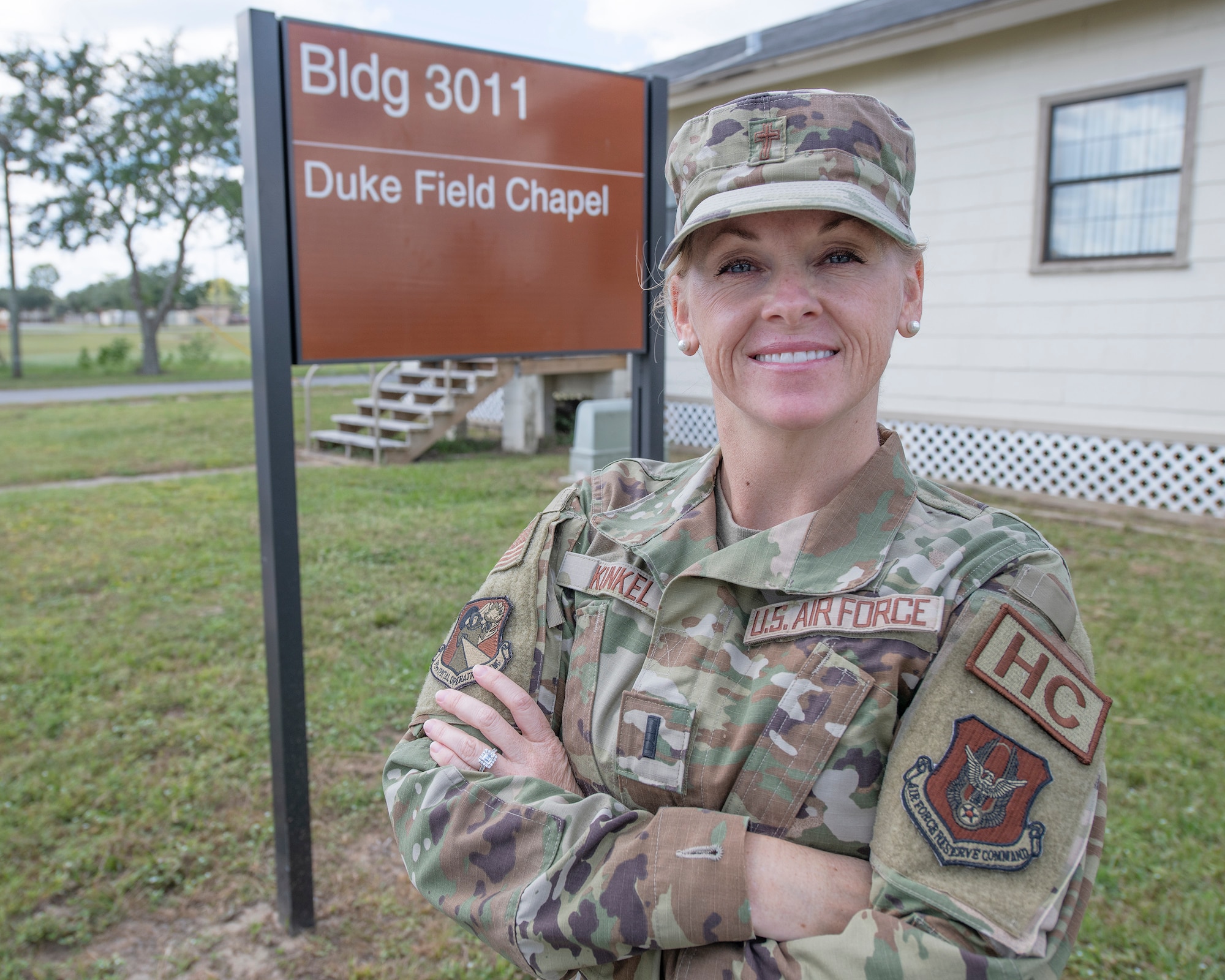 A female, military chaplain stands and poses in front of the chapel sign.