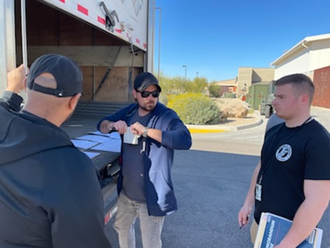 Men talk next to open truck.