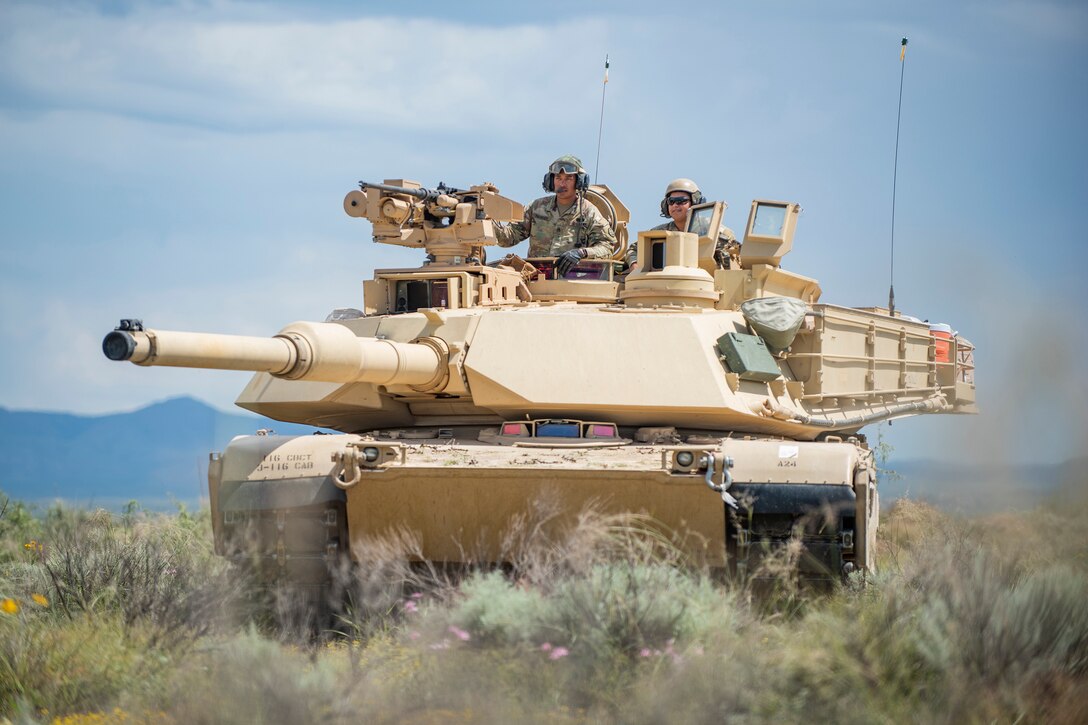 Two soldiers sit in a tank in a desert.