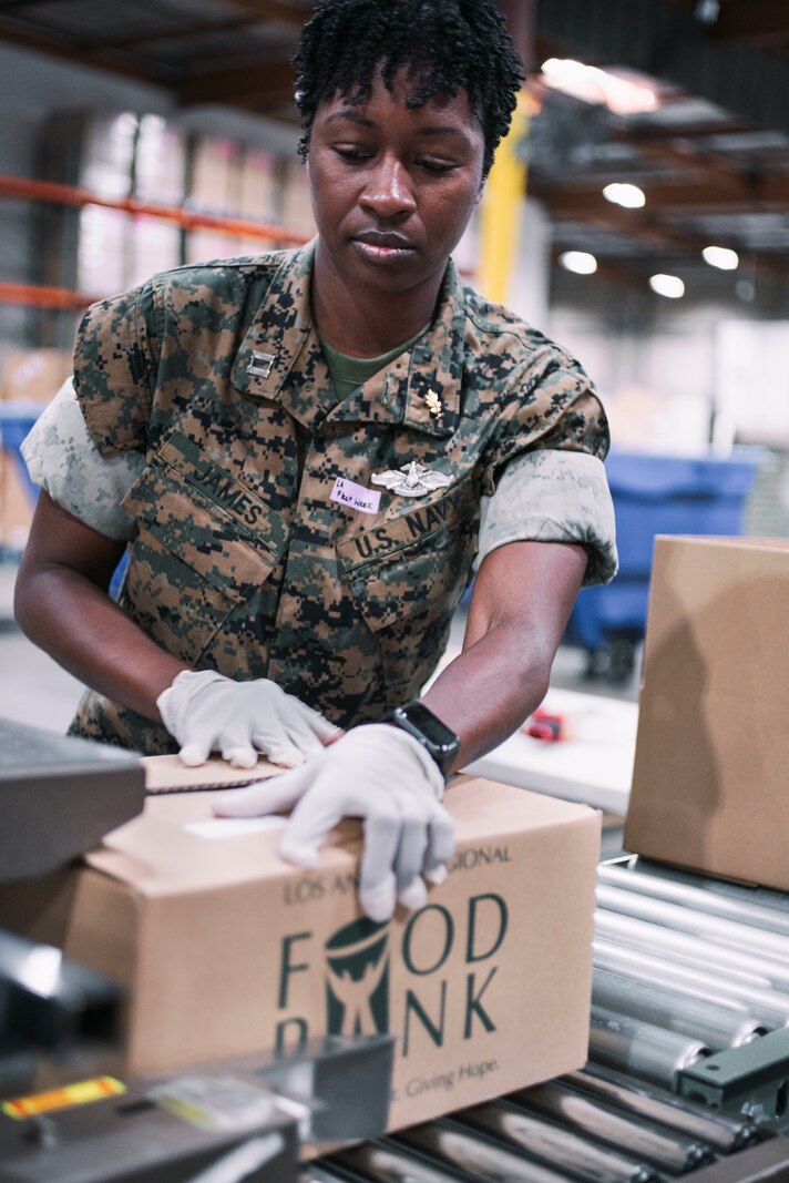 U.S. Navy Lt. Kavina James, the shock trauma platoon officer in charge assigned to 1st Medical Battalion, Task Force Los Angeles, moves a box of food down the assembly line while volunteering at the Los Angeles Regional Food Bank in Commerce, California, May 28, 2022.