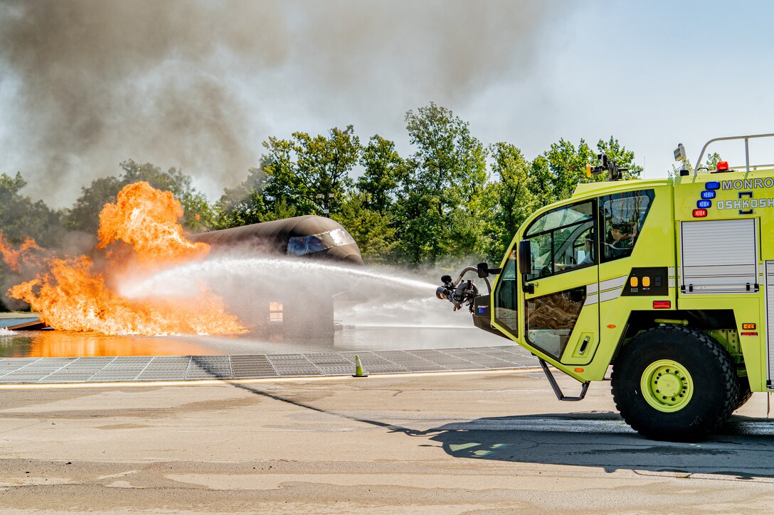 Firefighters with the 914th Fire Emergency Services control a firetrucks water cannon to put out a simulated aircraft's fire during training.