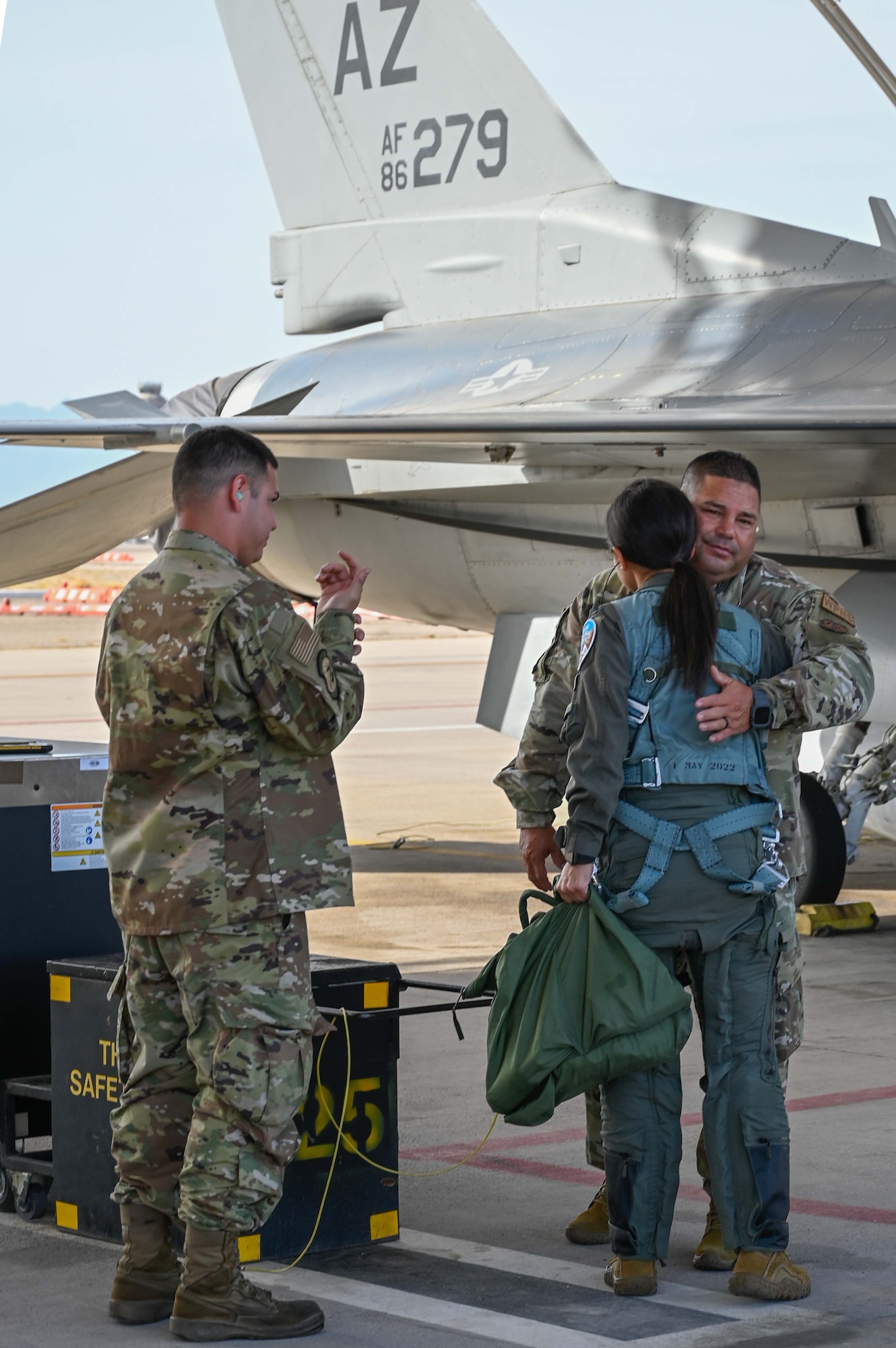 Senior Airman Raul Basurto III, an F-16 crew chief looks on as Master Sgt. Raul Basurto, Jr., 195th Fighter Squadron aircraft orndance systems supervisor, hugs his cousin, 1st Lt. Alyssa Majuta, before launching her on an F-16 training mission above the skies of southern Arizona. (U.S. Air National Guard photo by Maj. Angela Walz)