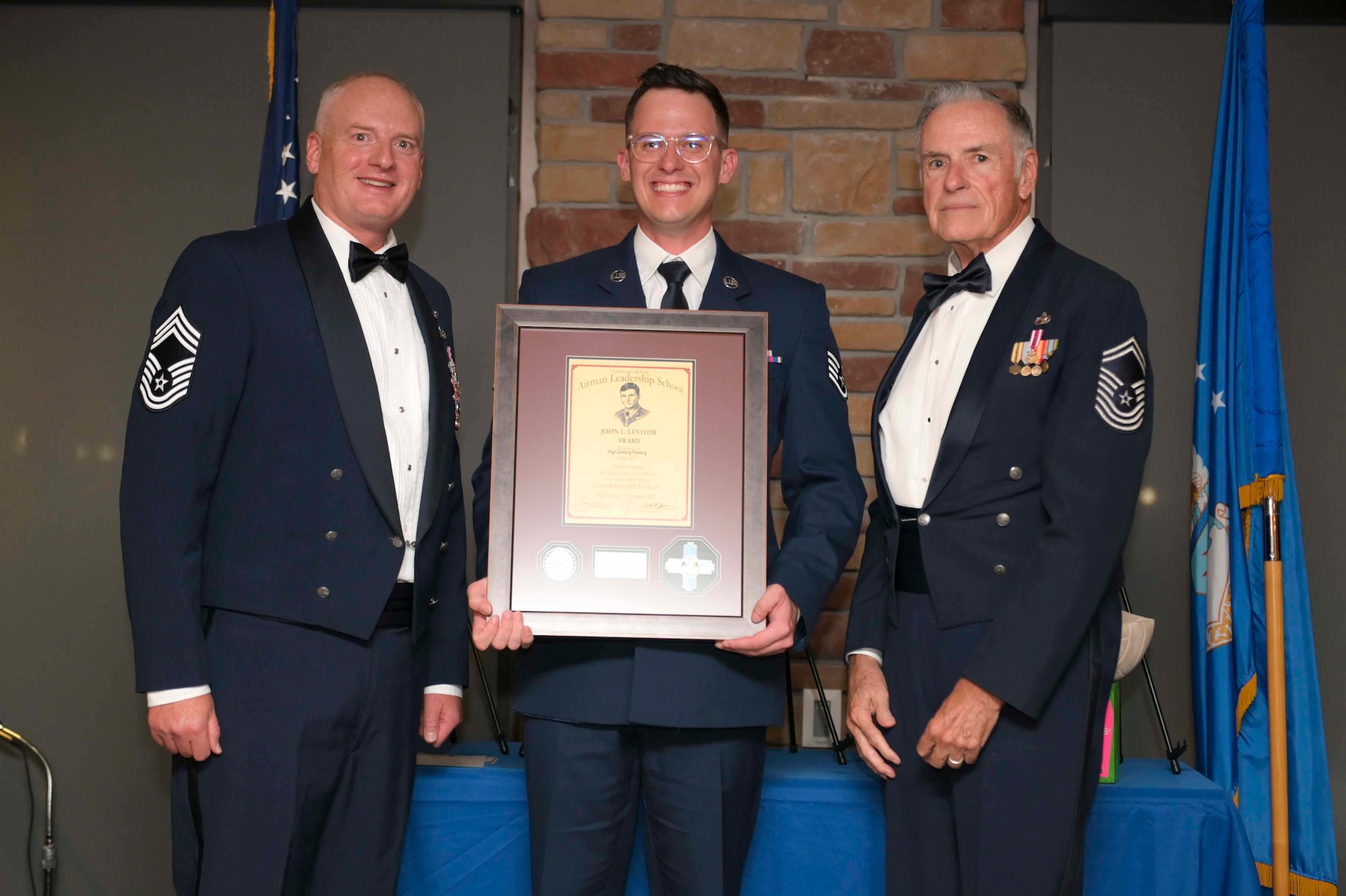U.S. Air Force Staff Sgt. Zachary Freeberg, center, accepts the John L. Levitow Award from U.S. Air Force Chief Master Sgt. Mark Teusch, 49th Component Maintenance Squadron senior enlisted leader, left, and retired U.S. Air Force Chief Master Sgt. Mac during an Airman Leadership School graduation at Holloman Air Force Base, New Mexico, Sept. 22, 2022. The Levitow award is presented to the student demonstrating the highest level of leadership and scholastic performance, and is determined by the assignment of points by their peers. (U.S. Air Force photo by Tech. Sgt. Victor J. Caputo)