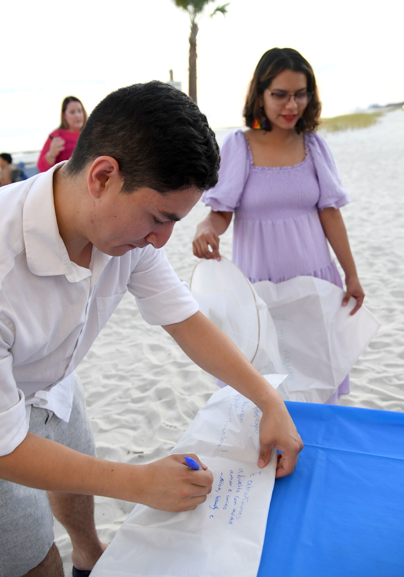 U.S. Air Force Staff Sgt. Nick Dominguez, 334th Training Squadron curriculum developer, writes a message on a lantern during the Gold Star Families Sky Lantern Release on the Biloxi Beach, Mississippi, Sept. 23, 2022. The event, hosted by Keesler Air Force Base, included eco-friendly sky lanterns released in honor of fallen heroes. (U.S. Air Force photo by Kemberly Groue)