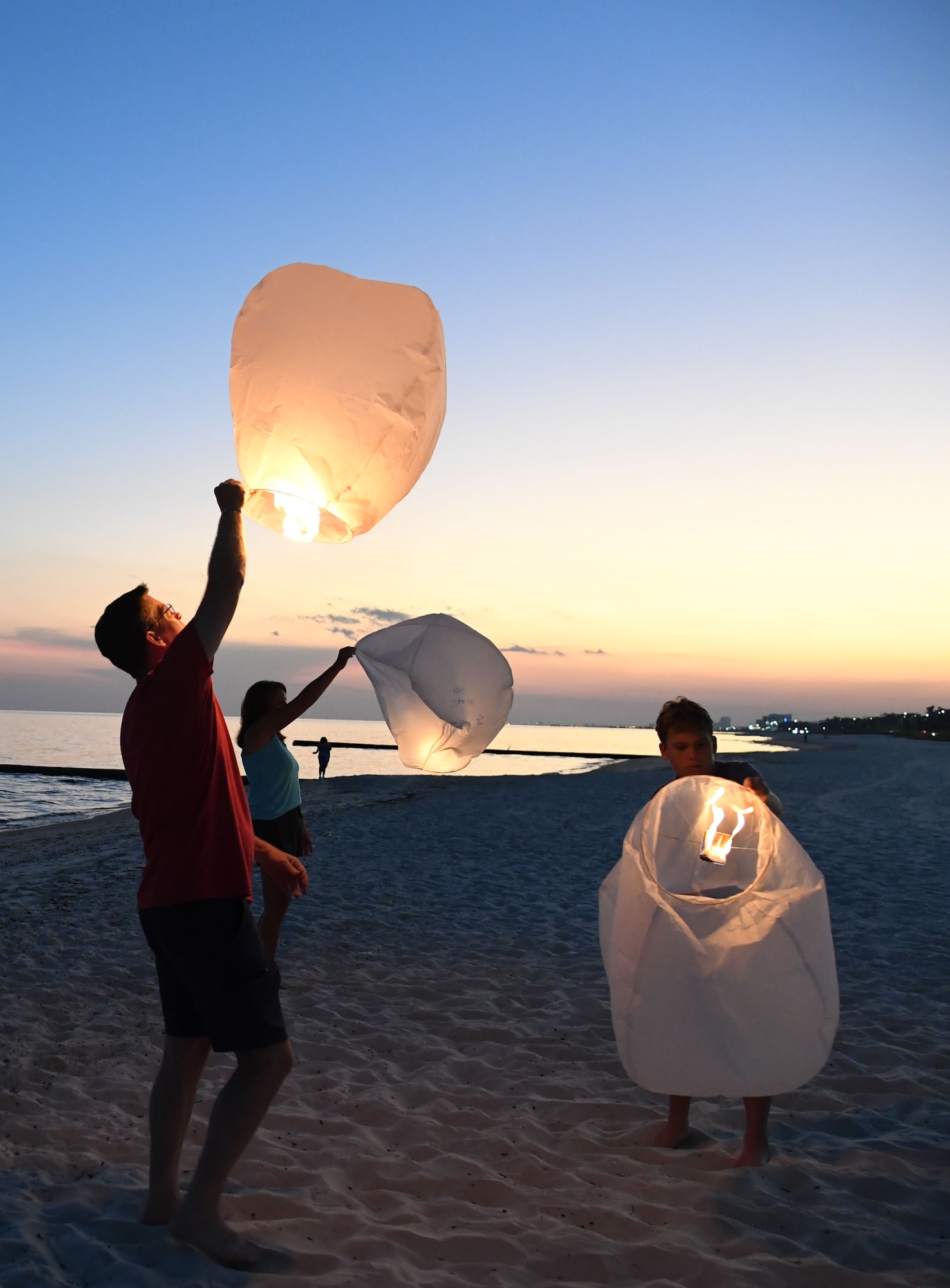 U.S. Air Force Col. C. Mike Smith, Second Air Force A3/6 commander, and his family light lanterns during the Gold Star Families Sky Lantern Release on the Biloxi Beach, Mississippi, Sept. 23, 2022. The event, hosted by Keesler Air Force Base, included eco-friendly sky lanterns released in honor of fallen heroes. (U.S. Air Force photo by Kemberly Groue)