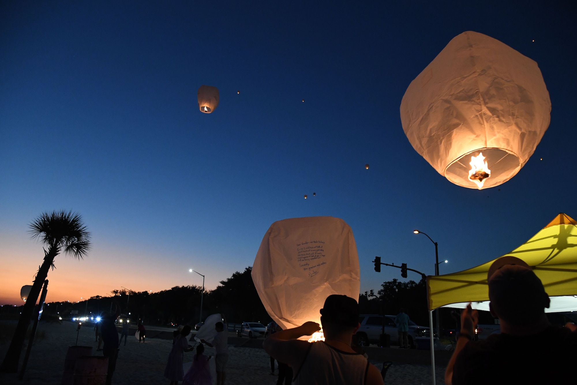 Military family members light and release lanterns during the Gold Star Families Sky Lantern Release on the Biloxi Beach, Mississippi, Sept. 23, 2022. The event, hosted by Keesler Air Force Base, included eco-friendly sky lanterns released in honor of fallen heroes. (U.S. Air Force photo by Kemberly Groue)
