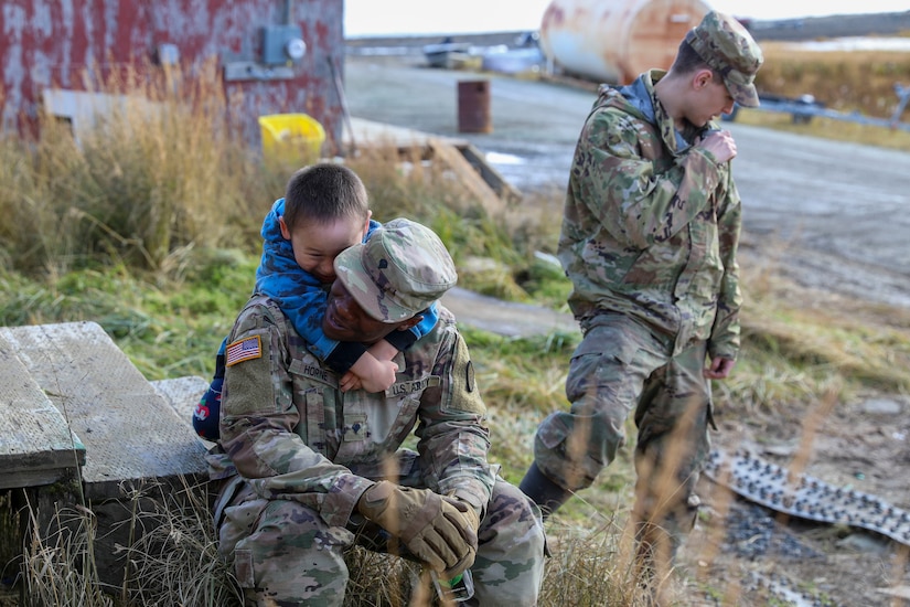 Alaska Army National Guard Spc. Jakobe Horne, right, an information technologist specialist with Headquarters and Headquarters Company,1st Battalion, 207th Aviation Regiment from Anchorage, plays with a local child while taking a break from assisting with property damage as part of Operation Merbok Response in Toksook Bay, Alaska, Sept. 24, 2022. More than 130 members of the Alaska Organized Militia, which includes members of the Alaska National Guard, Alaska State Defense Force and Alaska Naval Militia, were activated following a disaster declaration issued Sept. 17 after the remnants of Typhoon Merbok caused dramatic flooding across more than 1,000 miles of Alaskan coastline. (Alaska National Guard photo by 1st Lt. Balinda O'Neal)