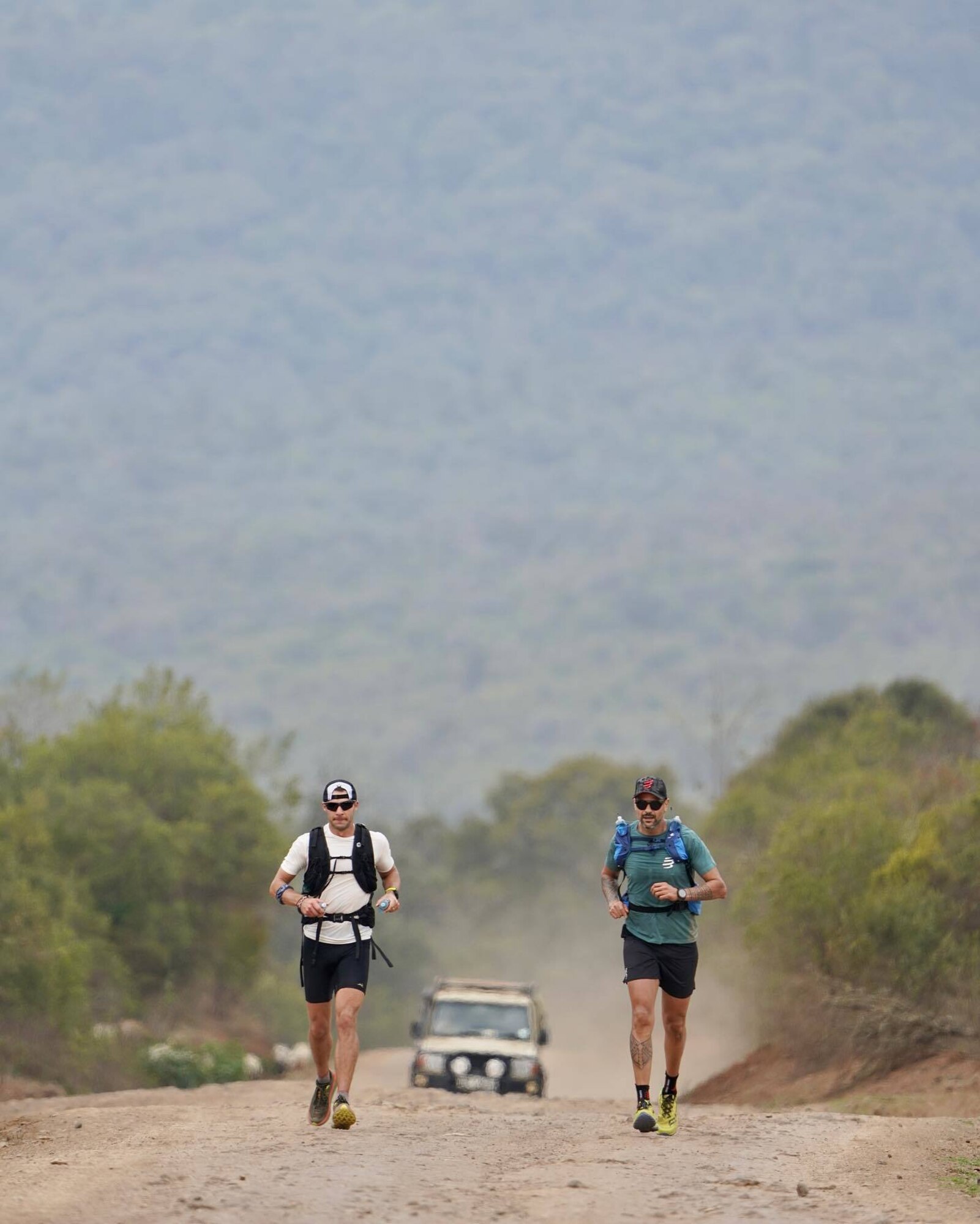 Airman runs on dirt road through African savannah.