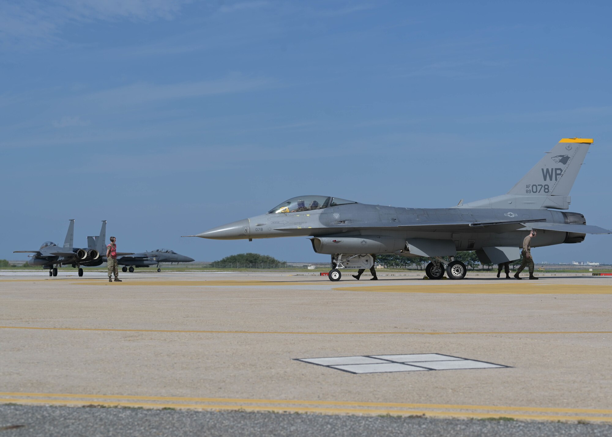 An 80th Fighter Squadron F-16 Fighting Falcon sits on the flightline as two Republic of Korea Air Force F-15K Slam Eagles assigned to the 110th Fighter Squadron taxi at Kunsan Air Base, Republic of Korea, Sept. 22, 2022. The two nations routinely host training events aimed at increasing their mission focus and interoperability. (U.S. Air Force photo by Staff Sgt. Isaiah J. Soliz)