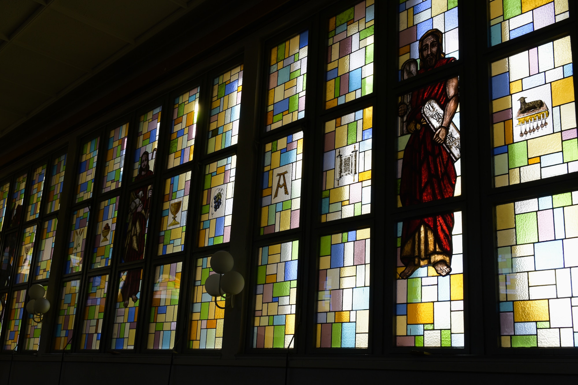 Image shows a stained glass window in a chapel, with images of Jesus on the glass.