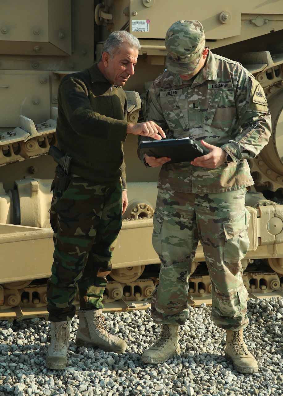 Two service members examine documents on a clipboard.