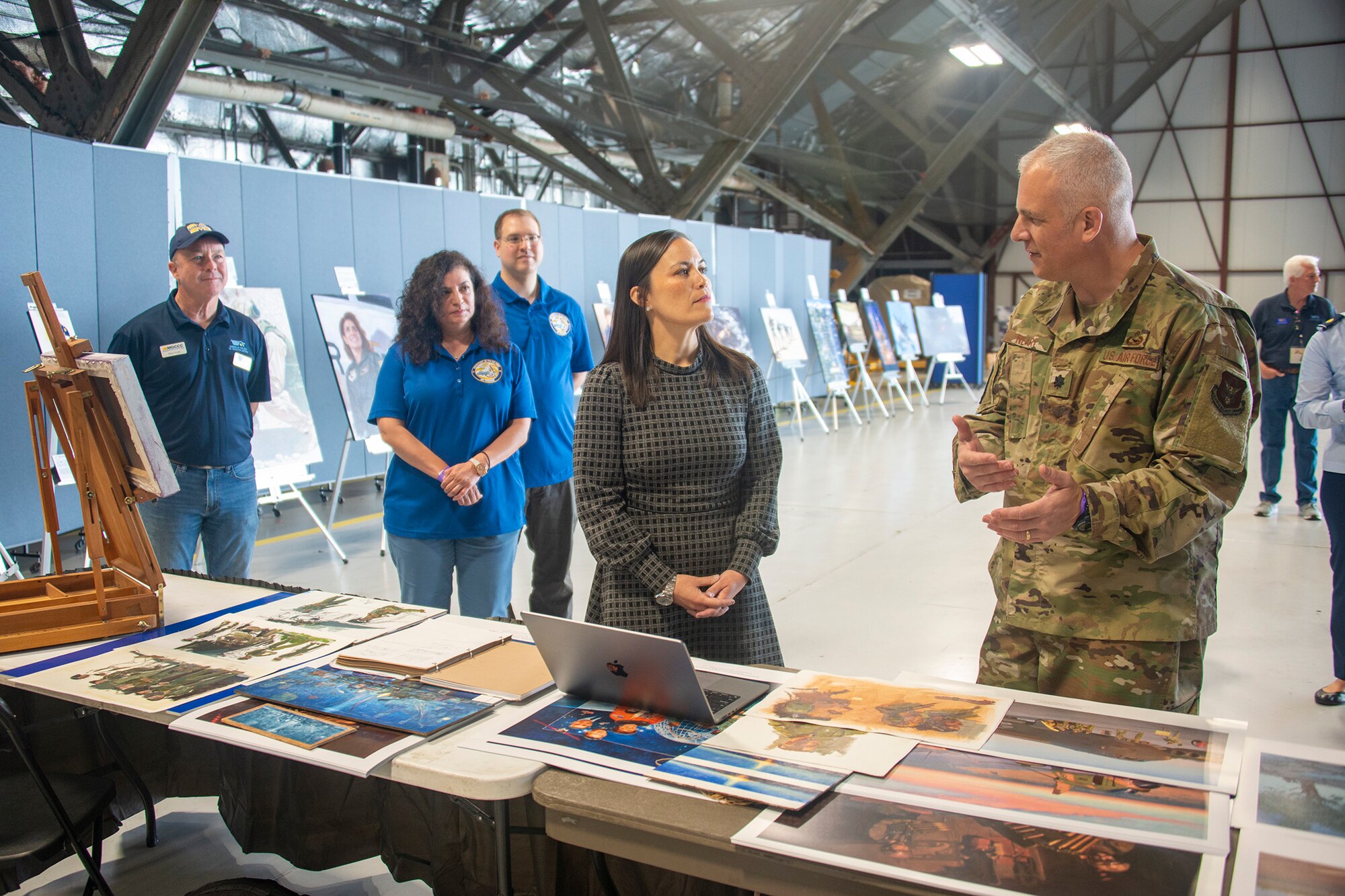 Under Secretary of the Air Force Gina Ortiz Jones (center) receives a briefing on plans for a heritage painting highlighting the 75th Anniversary of the Department of the Air Force from Lt. Col. Warren Neary, Air Force Reserve Command Office of History and Heritage combat artist (right), at a science, technology, engineering, arts and mathematics exhibit at the Joint Base Andrews 2022 Air and Space Expo Sept. 16, 2022.