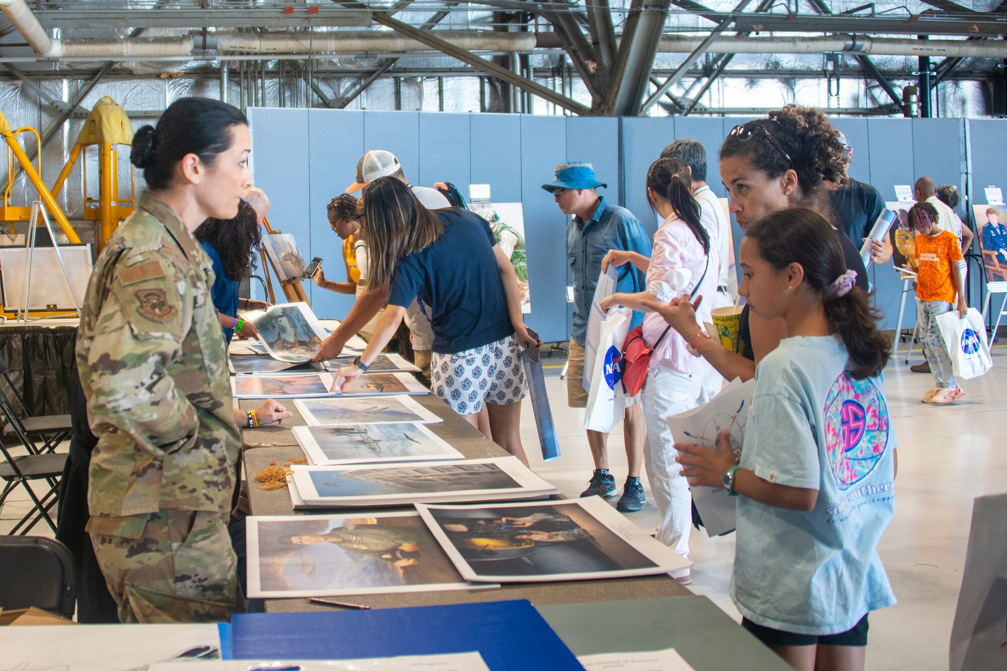 U.S. Air Force 2nd Lt. Kat Justen, Air Force Reserve Command Office of History and Heritage combat artist, signs and distributes lithographs while interacting with attendees to a science, technology, engineering, arts and mathematics exhibit at the Joint Base Andrews 2022 Air and Space Expo Sept. 18, 2022.