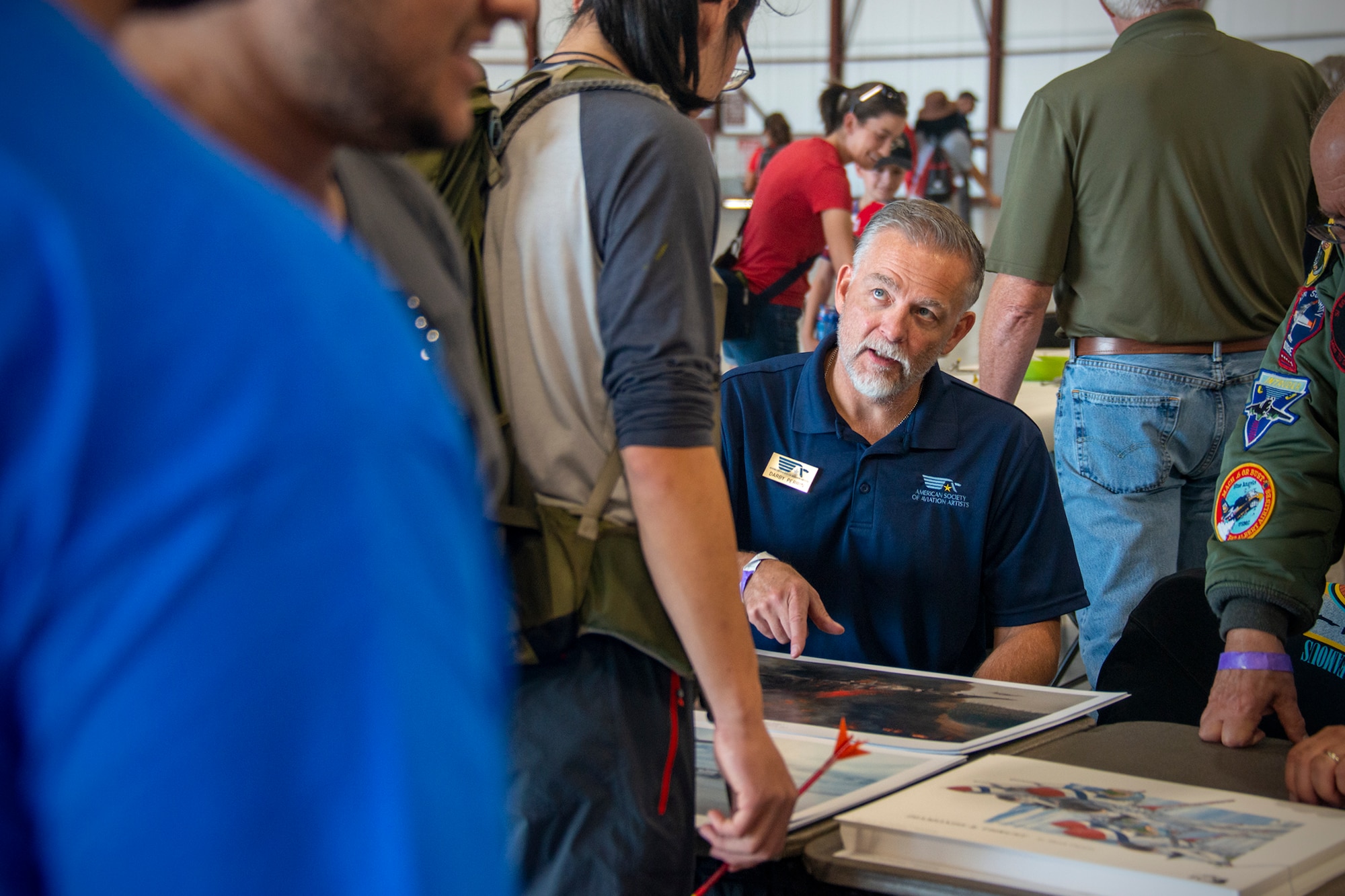 U.S. Air Force Senior Master Sgt. (ret.) Darby Perrin, Air Force Reserve Command Office of History and Heritage combat artist, signs and distributes lithographs while interacting with attendees to a science, technology, engineering, arts and mathematics exhibit at the Joint Base Andrews 2022 Air and Space Expo Sept. 17, 2022