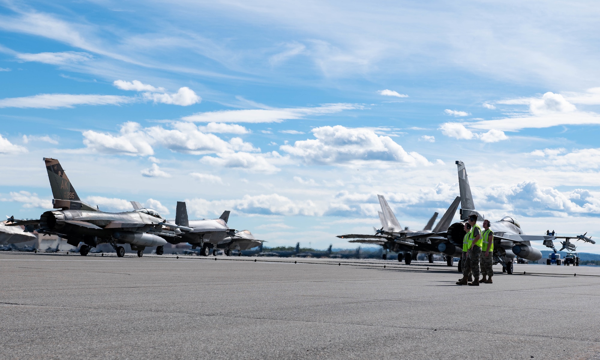 Airmen watch fighter jets taxi the runway