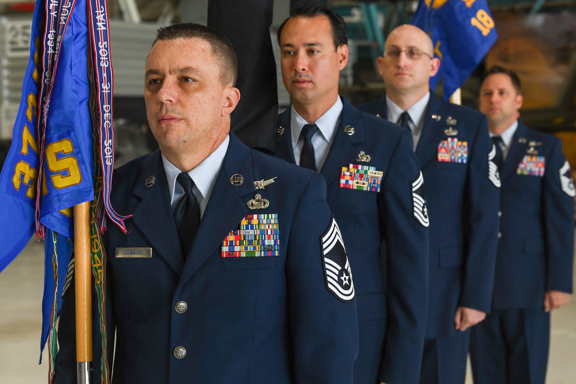 Military members stand in line holding flags.