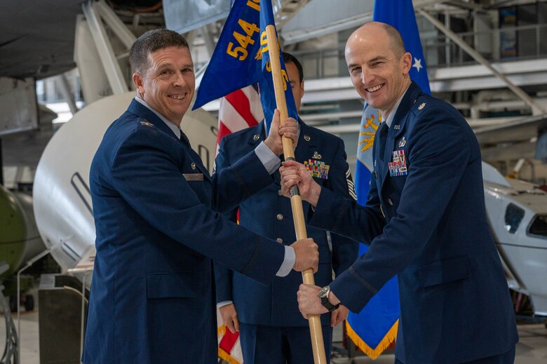 Two military members hold a flag at a ceremony.