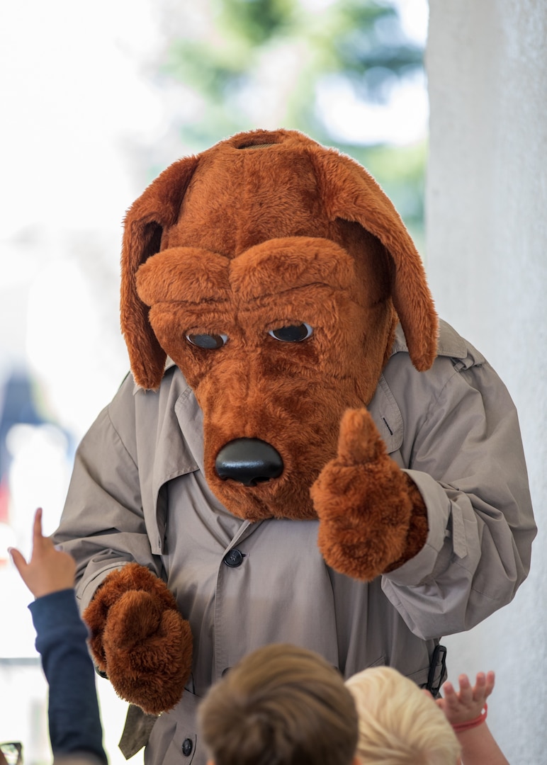 A person dressed in a brown dog costume with a detective coat on.
