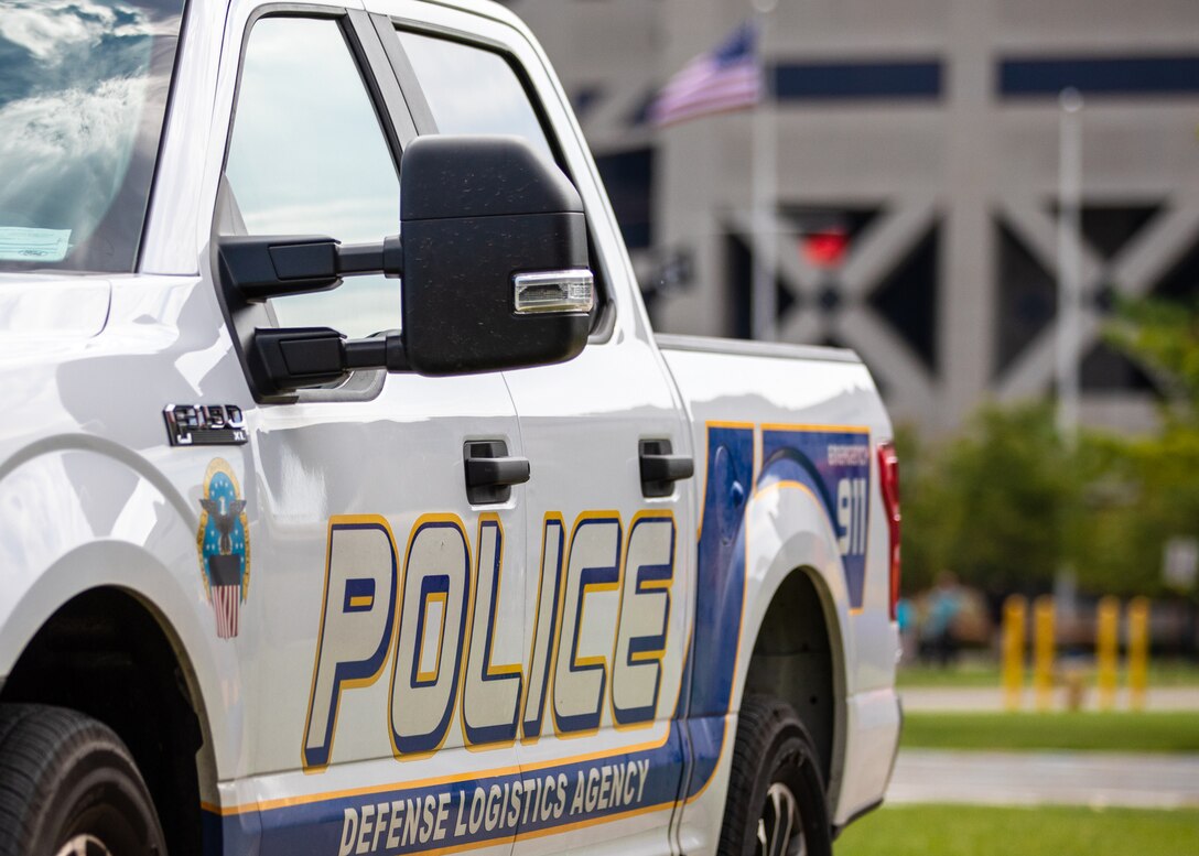 A white truck at a diagonal with police logos all over it.