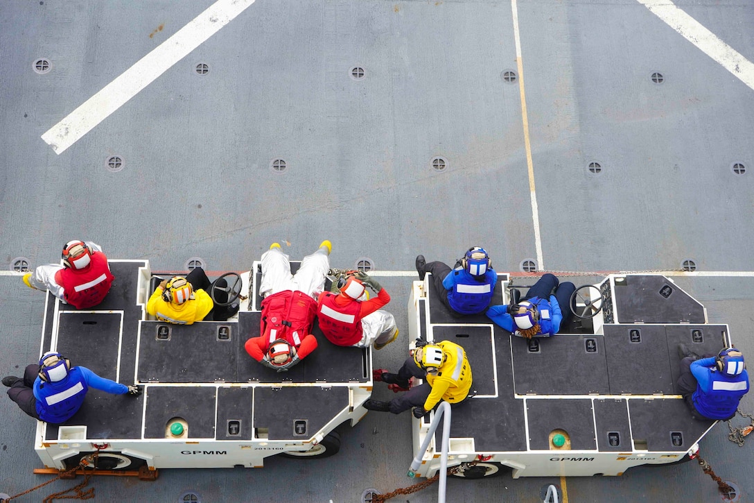 Sailors sitting on equipment.