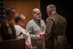 A couple is presented a flag. Close-up on the father's face as he is handed the flag from a man in Army dress uniform (MG Crane).