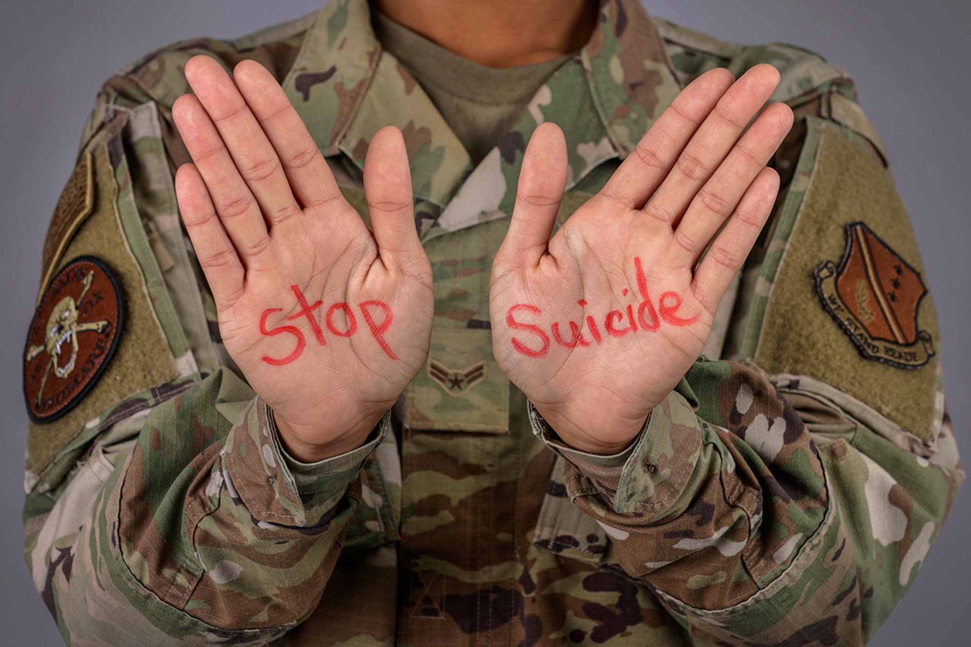 Airman holding hands out with the words Stop Suicide written on them.