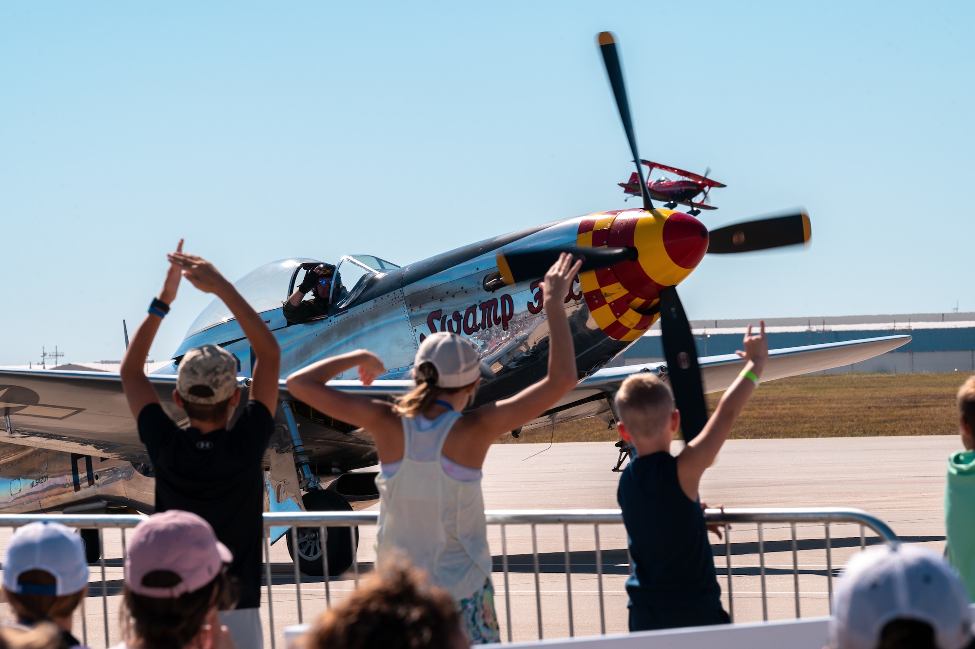 The children of local civic leaders wave to a P-51 Mustang as it passes them Sep. 25, 2022, at McConnell Air Force Base, Kansas.