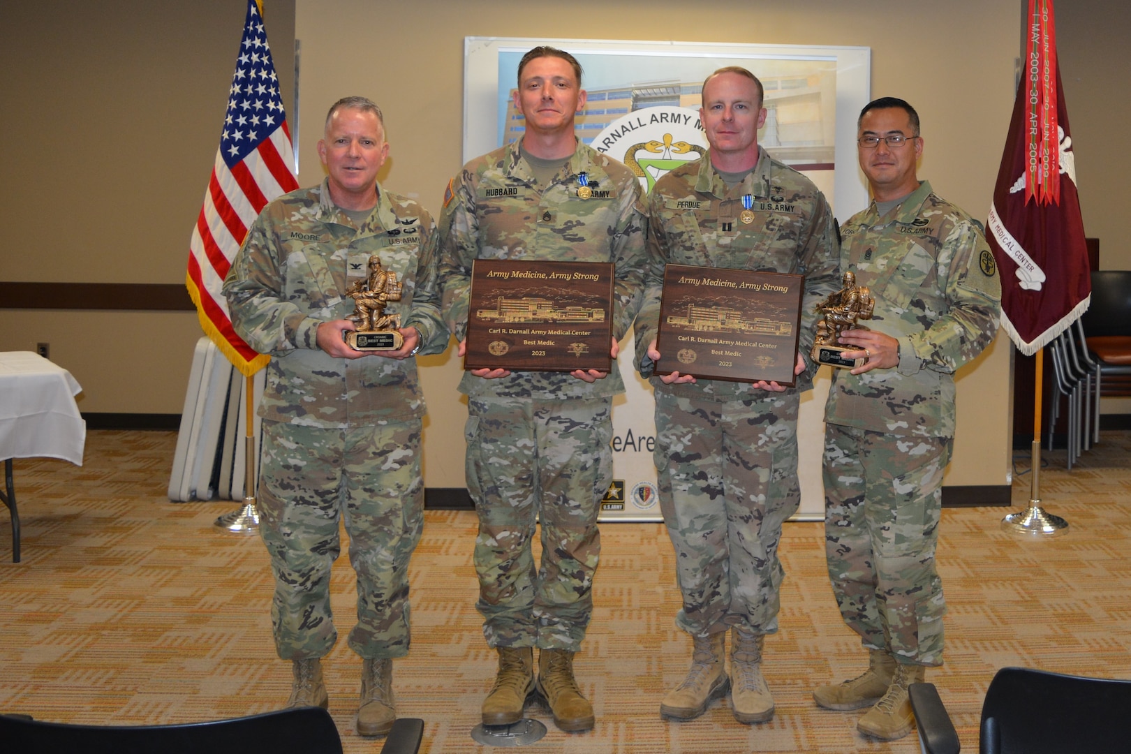 Fort Hood, Texas – Carl R. Darnall Army Medical Center command team, Col. Daniel Moore, commander, and Command Sgt. Maj. Anthony Forker Jr., present plaques and trophies to Staff Sgt. Phillip M. Hubbard, radiology specialist, CRDAMC, the 2023 winner, and Cpt. Matthew J. Perdue, physician assistant, runner-up of the CRDAMC Best Medic Competition in a ceremony, Sept. 9.