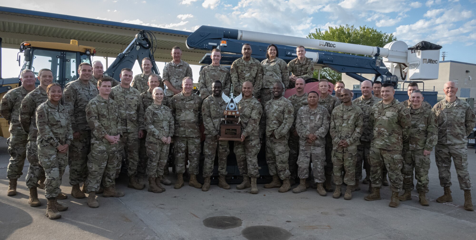 Airmen stand holding trophy.