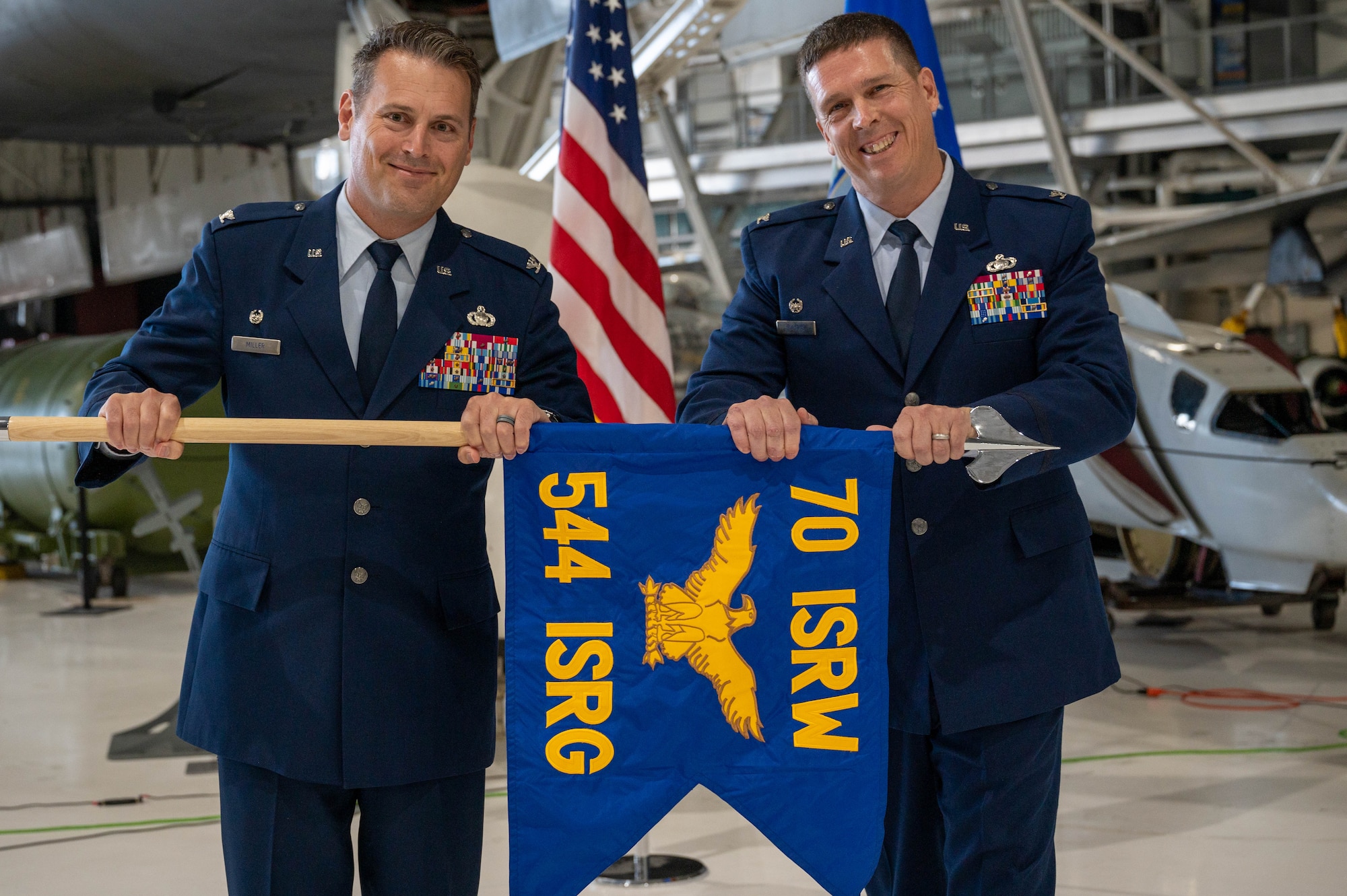 Two military members hold a flag at a ceromony.