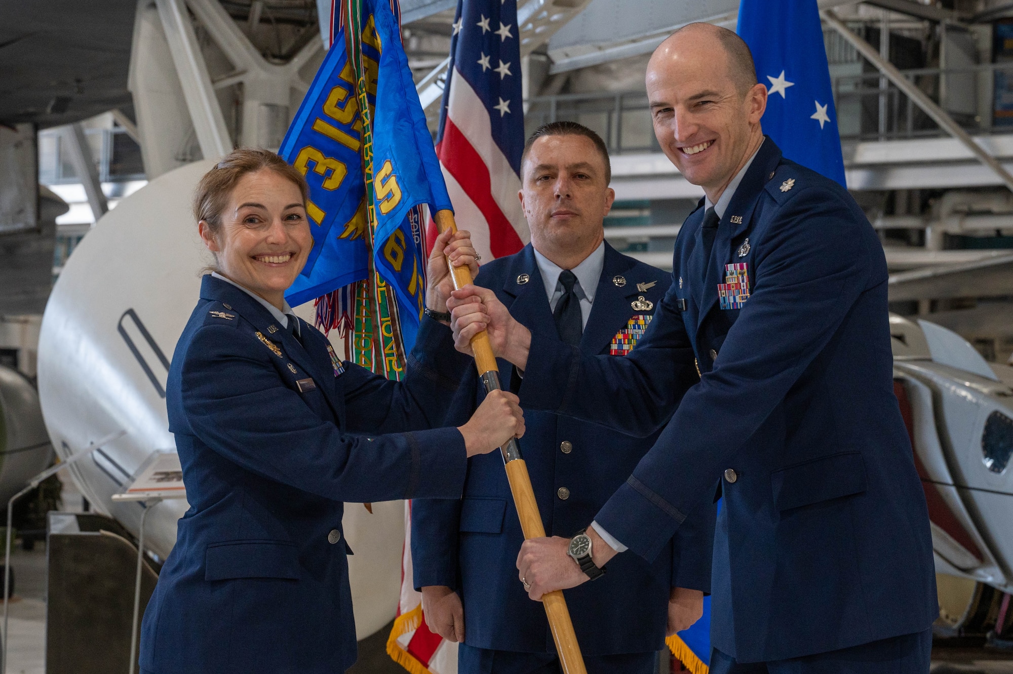 Two military members hold a flag at a ceremony.