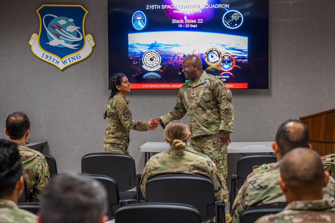 U.S. Space Force Lt. Col. Albert Harris, Commander of the 392nd Combat Training Squadron, presents a commander's coin to U.S. Air Force Staff Sgt. Esmeralda Sanchez-Avila from the 216th Space Control Squadron during BLACK SKIES 22 at Vandenberg Space Force Base