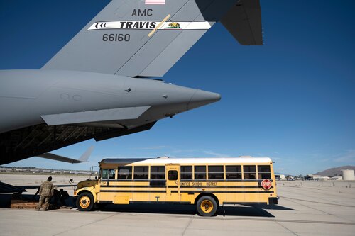 Um ônibus escolar se aproxima de um C-17 Globemaster III em 23 de setembro de 2022, na Base da Reserva Aérea de Março, Califórnia. Uma tripulação da Reserva do 301o Esquadrão de Transporte Aéreo realizou uma missão de três dias de 23 a 25 de setembro, para mover carga humanitária para o Haiti. Através do Programa Denton, três ônibus escolares doados do Distrito Escolar Unificado de San Diego foram transportados da ARB de março para o Haiti. (EUA Foto da Força Aérea pelo Aerór Sênior Jonathon Carnell)