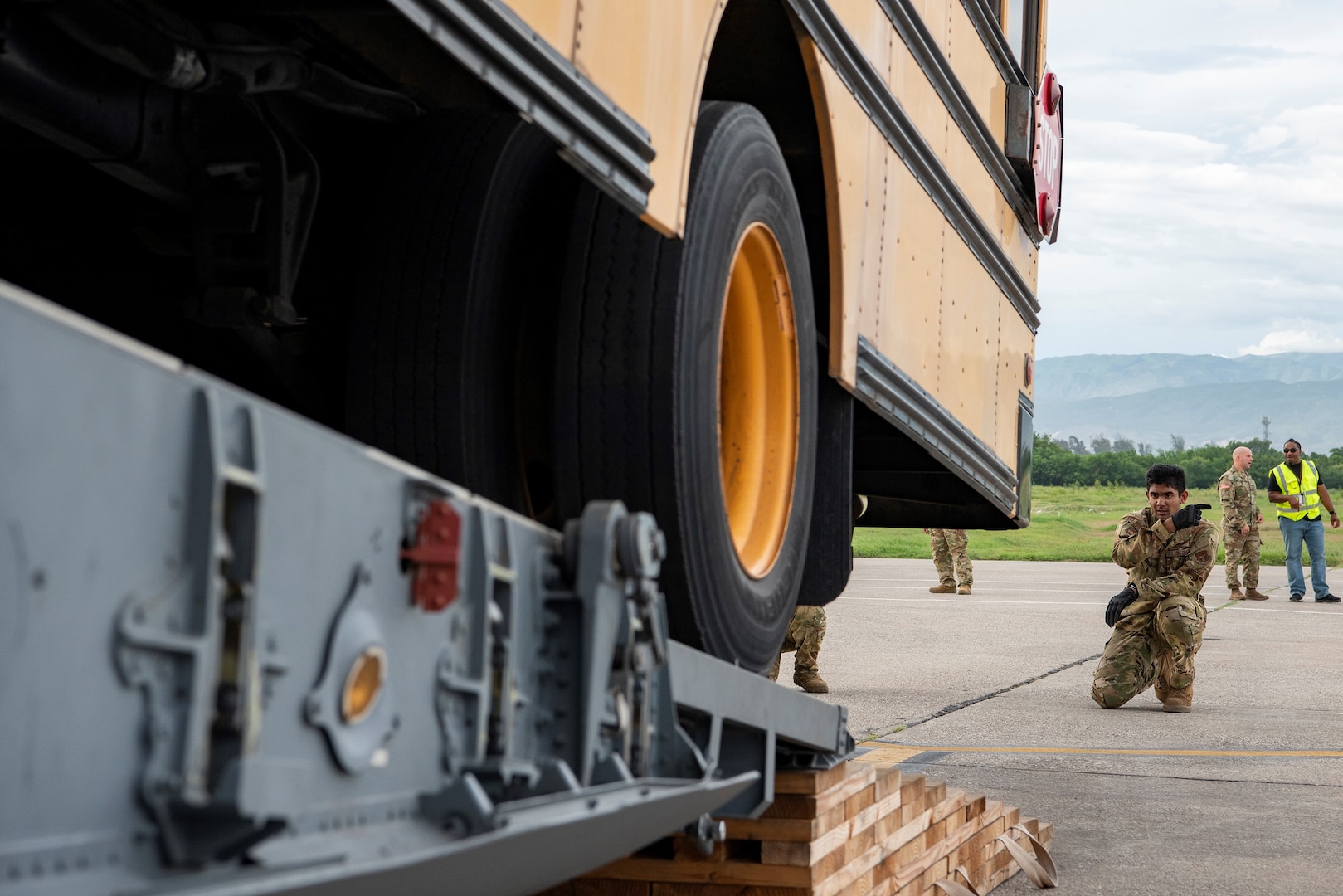 Airman 1st Class Romit Raj, 301st Airlift Squadron, guides a school bus off of a C-17 Globemaster III on Sept. 24, 2022, in Port-au-Prince, Haiti. The 349th Air Mobility Wing performed a three-day mission to move humanitarian cargo to Haiti. Through the Denton Program, three school buses donated from San Diego Unified School District were transported from March Air Reserve Base, California, to Haiti.